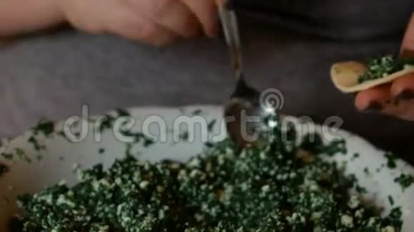 一位年长的妇女用熟练的方法用菠菜填充馄饨视频的预览图