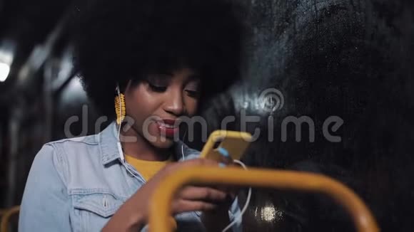 漂亮的非裔美国年轻女性在公共交通工具上使用智能手机晚上城市灯光背景视频的预览图