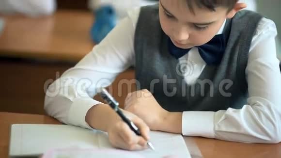 男生在教室里的笔记本上写字视频的预览图