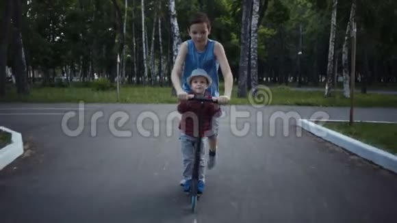 两个兄弟在一个夏天的公园里骑着踢滑板车视频的预览图