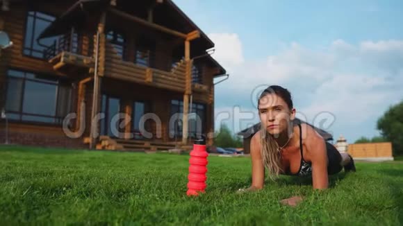 美丽的深色头发的女人在一个大房子的背景下从事健身和为新闻界做木板运动视频的预览图