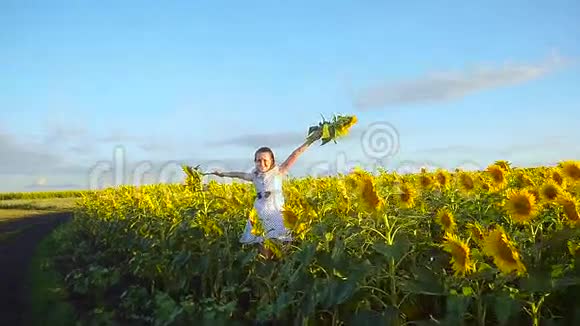 开朗的女孩捧着黄花葵青春的女孩在向日葵的田野里视频的预览图
