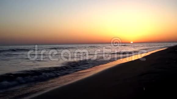 平静的缓慢的令人满意的海浪拍打在沙滩上海岸海岸线上如画般温暖的傍晚橙色的日落海景视频的预览图