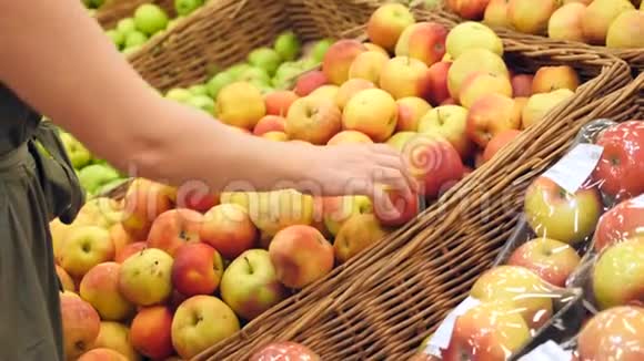 一个女人在蔬菜货架上的超市里买蔬菜和水果人类选择苹果慢动作4k视频的预览图