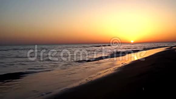 在令人印象深刻的温暖的傍晚橙色的日落海景中令人满意的平静的慢波撞击在沙滩海岸海岸线上视频的预览图