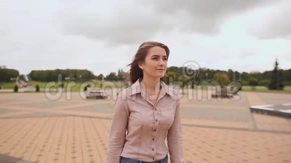穿衬衫和牛仔裤长发的年轻女孩在城市公园里视频的预览图