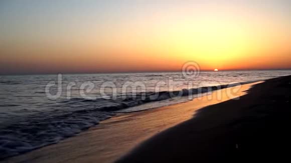 在美丽温暖的傍晚橙色的夕阳西下沙滩海岸海岸线上缓慢而令人满意的平静海浪拍打着视频的预览图