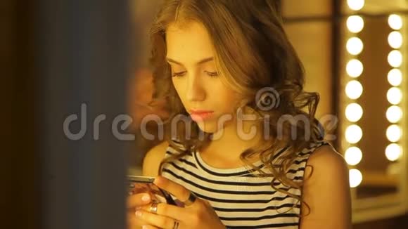 开朗的女孩在理发看着她的智能手机吹了一个空气吻视频的预览图