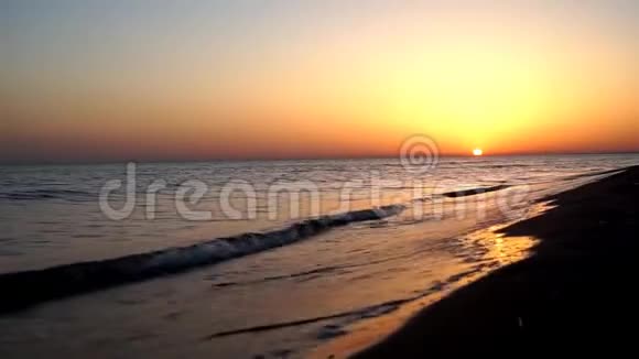 令人满意的缓慢平静的海浪拍打在沙滩海岸海岸线在令人难以置信的温暖的傍晚橙色的日落海景视频的预览图