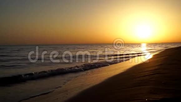 令人满意的缓慢平静的海浪拍打在沙滩上海洋海岸海岸线在可爱温暖的傍晚橙色的日落海景视频的预览图
