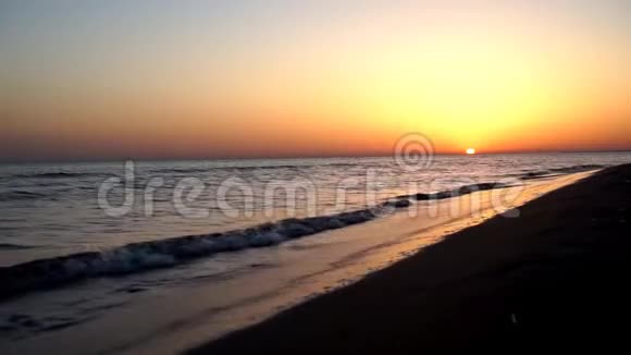 平静令人满意的慢波拍打沙滩海岸线在壮观的温暖夜晚橙色日落海景视频的预览图