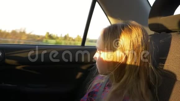 夏夜乘汽车旅行的小女孩窗外的乡村景象女生特写手持镜头视频的预览图