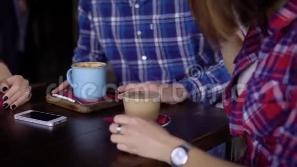 特写餐厅或咖啡馆的桌子女人和男人手杯子里有咖啡和饮料桌子上有智能手机视频的预览图