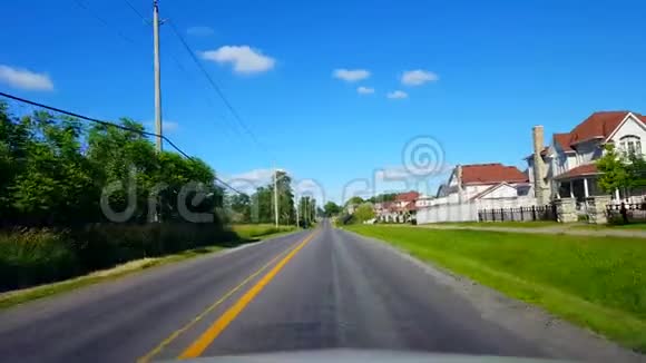 在夏日期间驾驶住宅城市道路上的树木沿美丽的阳光街的司机视角POV视频的预览图
