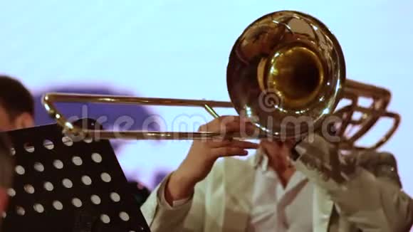 特写镜头一个铜管乐队的音乐家在白色衣服的长号上独奏视频的预览图