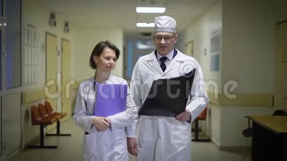 医生一男一女走上医院走廊相互交流医务人员把文件夹放在视频的预览图
