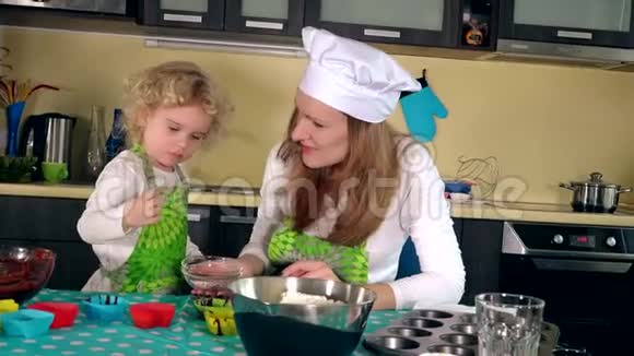 可爱的女孩和妈妈在厨房品尝糖果有女儿的女人做松饼视频的预览图
