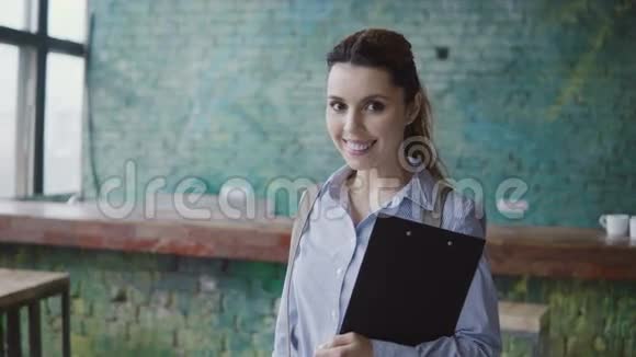 年轻成功的高加索女人看着镜头微笑的肖像女人在现代办公室里拿着文件视频的预览图