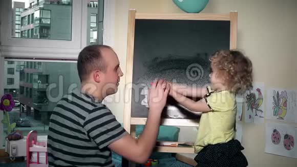 爱爸爸在家里用粉笔板教他的孩子写字母视频的预览图
