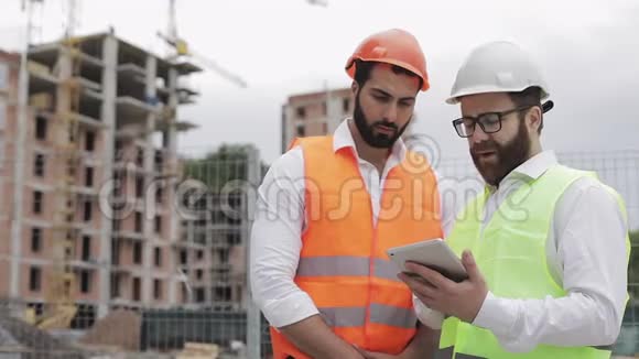 建筑工人和建筑师正在讨论站在附近的现代商务中心的建设计划视频的预览图