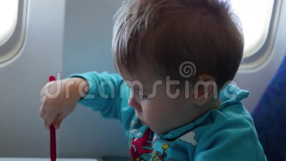 一个孩子坐在靠近窗户的飞机上画画视频的预览图
