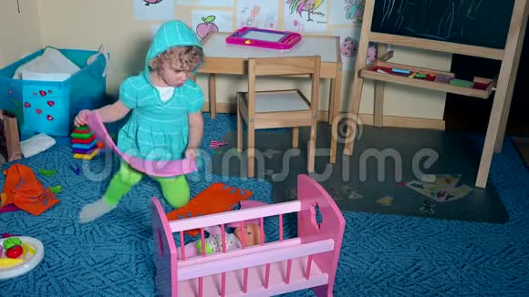 可爱的蹒跚学步的小女孩把娃娃躺在玩具床上盖上毯子视频的预览图