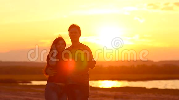 快乐的女孩和男人在日落时对着美丽的天空自拍他们幸福地相爱了视频的预览图