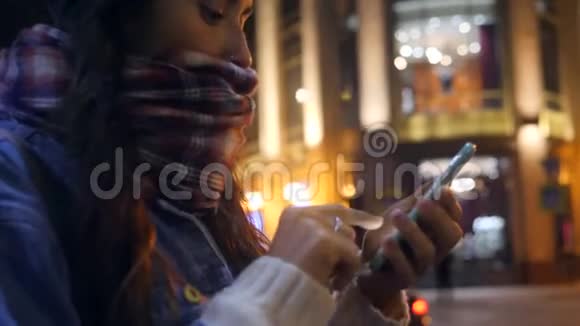 迷人的年轻混合种族妇女使用手机在夜间圣彼得堡街头4K慢动作俄罗斯视频的预览图