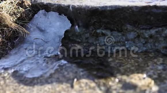 冰冷干净的水流穿过岩石上解冻的雪视频的预览图