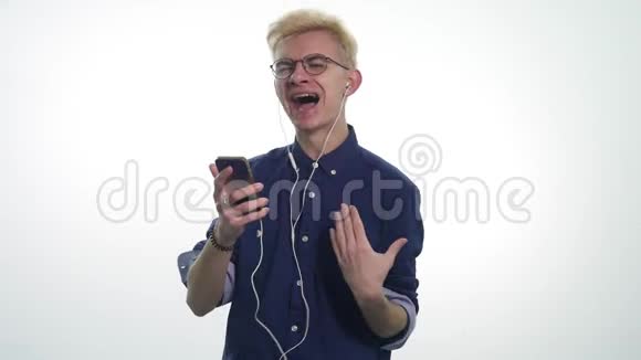 年轻的帅哥在白色背景下用耳机唱歌跳舞听音乐视频的预览图