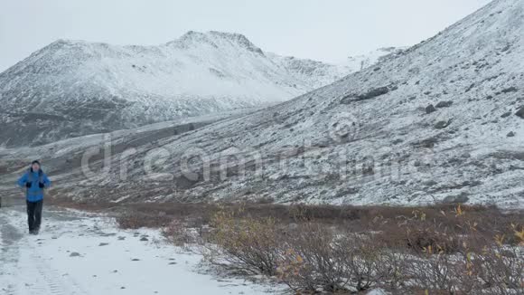 一个背着背包的人正沿着山间的一条雪道走着视频的预览图