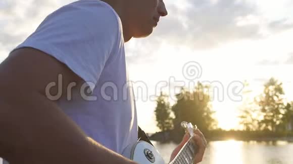 吉他手在户外傍晚日落时演奏电吉他和弦视频的预览图