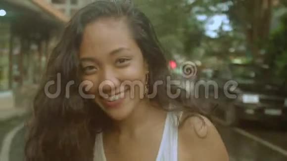 美丽的卷发亚洲女孩走在巴厘岛的街道上视频的预览图