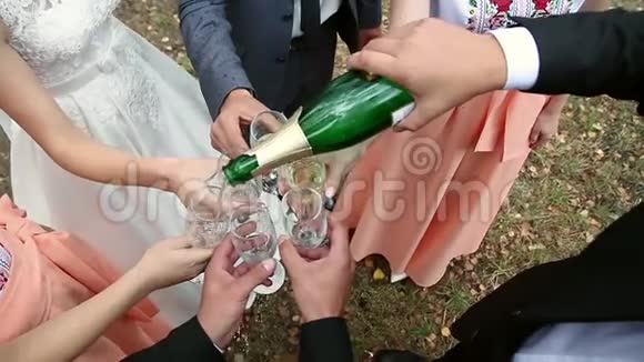 新婚夫妇和客人将香槟倒入玻璃杯中视频的预览图