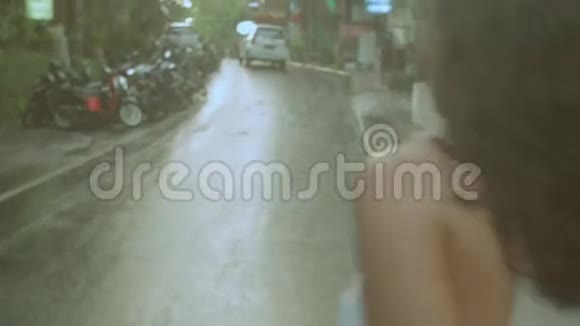 幸福美丽的年轻女子沿着潮湿的道路行走视频的预览图