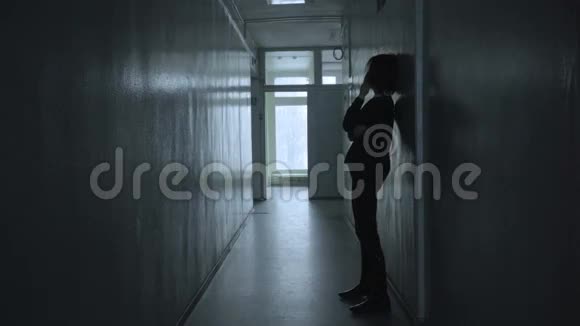 孤独的女人站在沉闷的走廊里扭动着视频的预览图