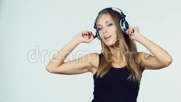 戴着耳机的金发美女在白色背景下跳舞视频的预览图