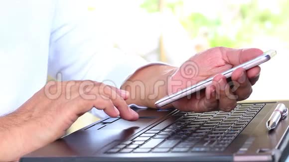 商人使用他的笔记本电脑和智能手机视频的预览图