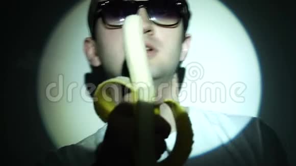 戴墨镜的男人吃光光束的香蕉视频的预览图
