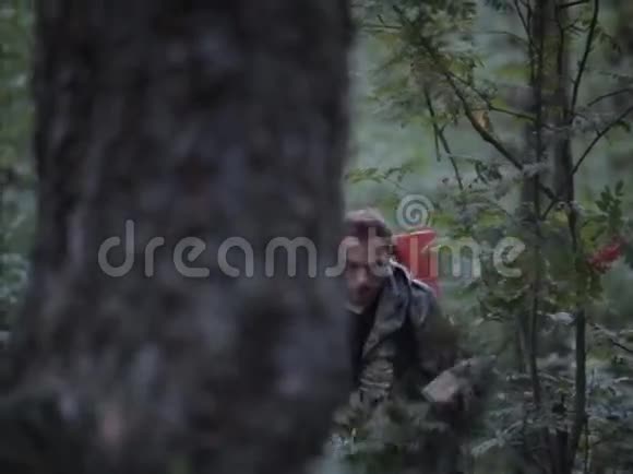 身穿迷彩制服背包的游客穿过森林猎人探索领土环顾四周视频的预览图