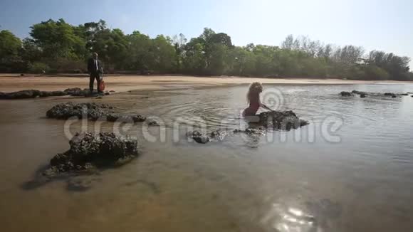 穿着泳衣的女孩沉浸在海吉他手的外表和演奏中视频的预览图