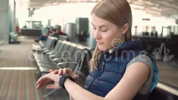 美丽的女人在机场使用智能手表和智能手机收到朋友的留言视频的预览图