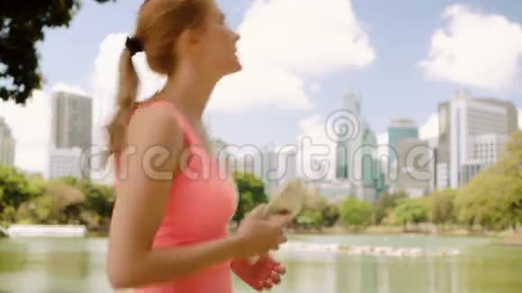 女子跑步者在公园慢跑适合女性运动健身训练在她的智能手机上拍照视频的预览图