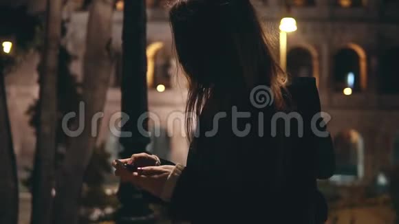 慢动作年轻漂亮的女人走在意大利罗马的斗兽场附近晚上使用智能手机视频的预览图