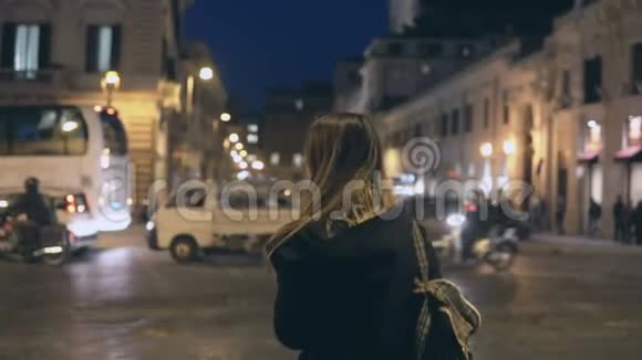 年轻的旅游妇女带着背包穿过交通道路游客在晚上环顾四周找到路视频的预览图
