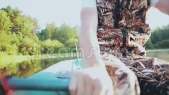男性手的特写镜头拿着森林湖中的桨和行在晴朗的天气里人摇桨视频的预览图
