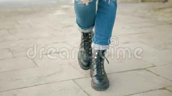 在鹅卵石街道上穿着黑色靴子的年轻女子的腿视频的预览图