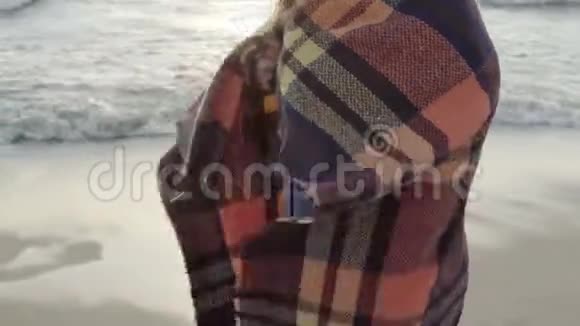 年轻女子站在海边望着远处孤独的女性享受海滩在寒冷的日子里挥手视频的预览图
