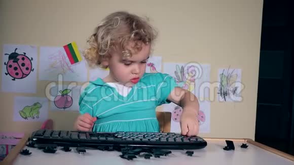 顽皮的小孩破坏桌子上的电脑键盘视频的预览图
