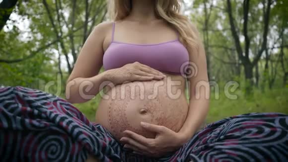 高加索孕妇长着波西米亚风格的长发大肚子上的白色麦亨迪新时代的宝宝期待视频的预览图